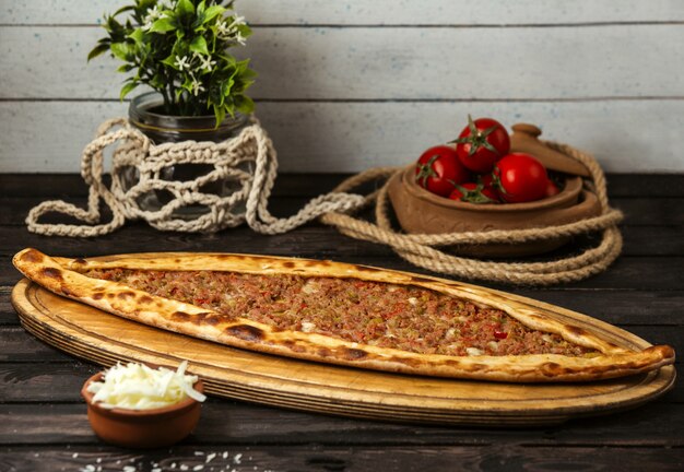 Turkish traditional pide with cheese and stuffed meat on a wooden board