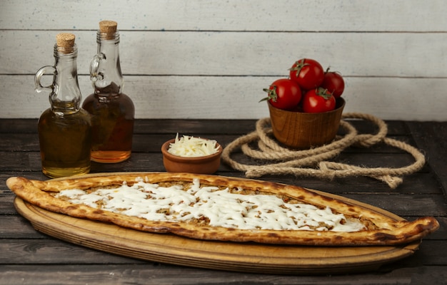 Foto gratuita pide tradizionale turco con carne e formaggio su un bordo di legno