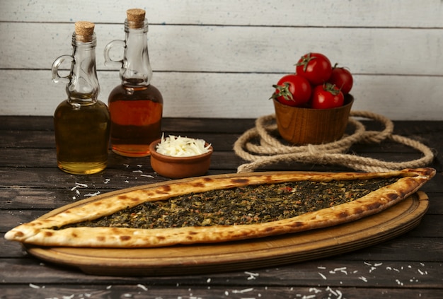 Free photo turkish traditional pide with stuffed meat and herbs on a wooden board