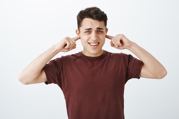 Turn that annoying sound off. Bothered displeased caucasian male coworker in red t-shirt