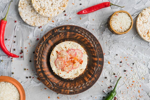 Turnip slices on puffed rice cakes seasoning with red chili and black peppers on concrete backdrop