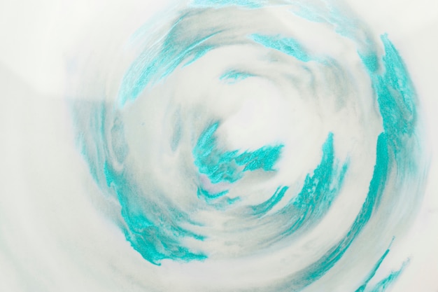 白い表面上の渦巻き模様のターコイズブルーのペイントストローク