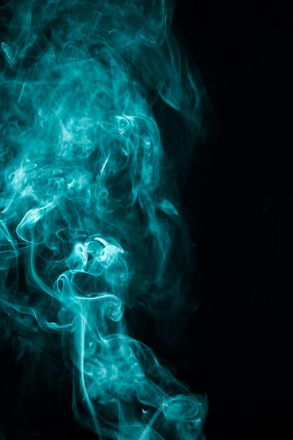 Turquoise smoke movement design against black background