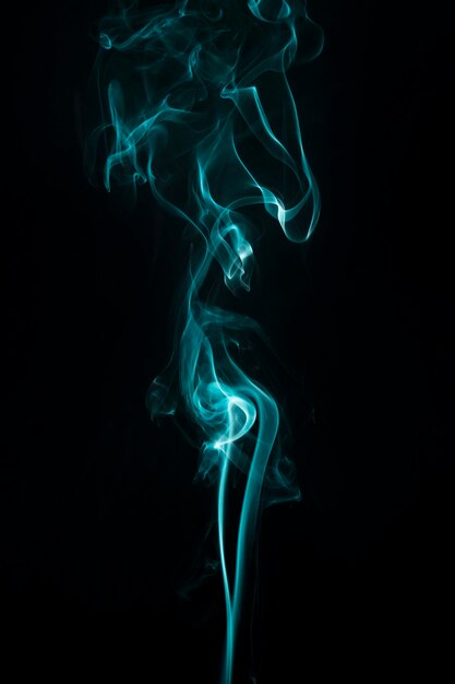 Turquoise smoke swirls upward on black background