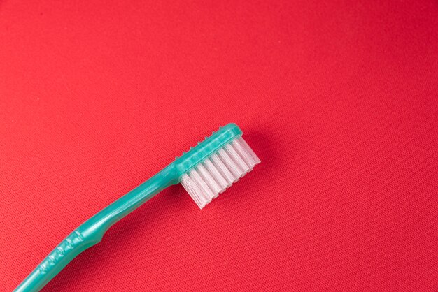 Turquoise toothbrush on the red surface