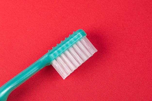 Бирюзовая зубная щетка на красной поверхности