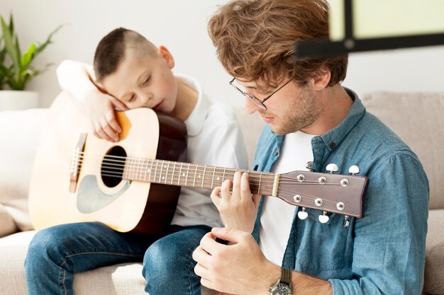 Tutor and boy learning how to play guitar