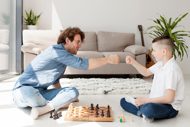 Репетитор и мальчик играют в шахматы на полу
