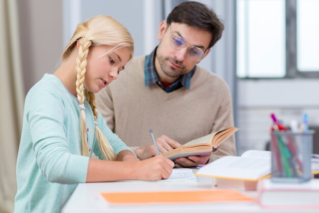 Tutor and girl at home writing