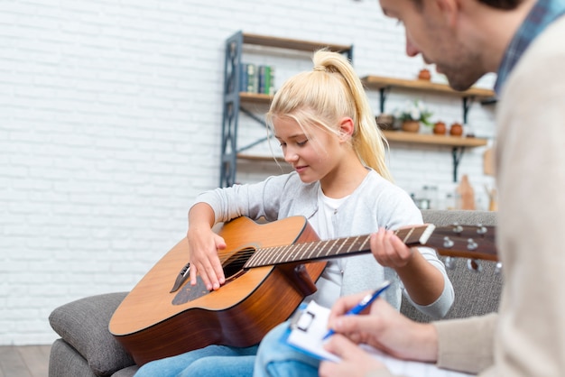 Tutor and young student learning how to play guitar
