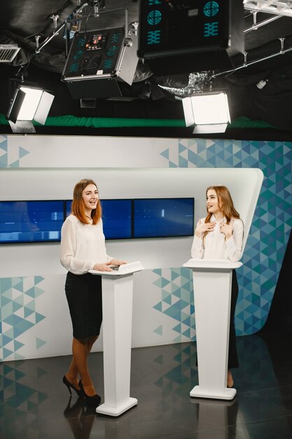 tv game show with two participants stand on tribunes. excited women in tv studio, filming tv show.