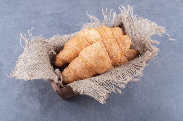 Tw fresh French Croissant in wooden box.