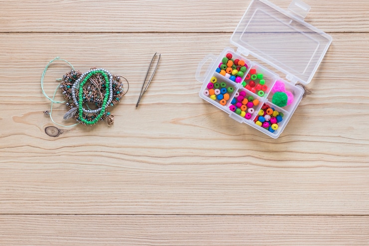 Free Photo tweezers; bracelet and beads in the white plastic box on wooden table