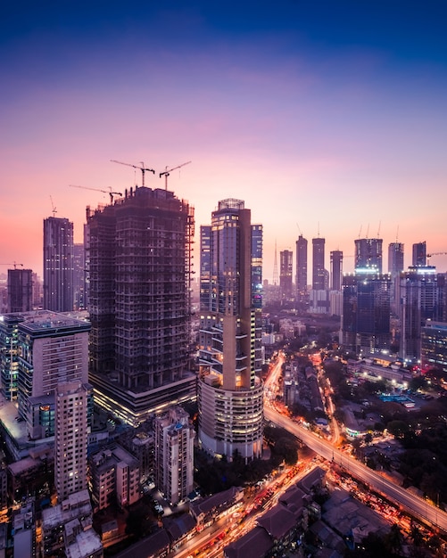 紫色の色調のムンバイの街並みの夕暮れの景色。建設中の建物や住宅用および商業用の高層ビルや高層ビルがたくさんあります。