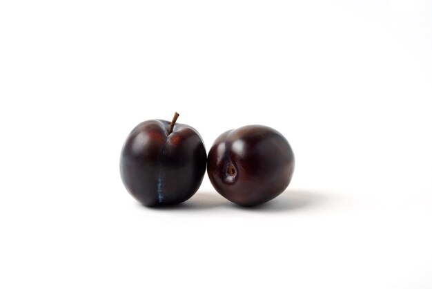 Twin black cherry plums isolated on white