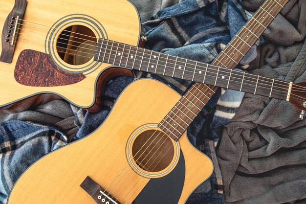 Two acoustic guitars on a cozy plaid top view