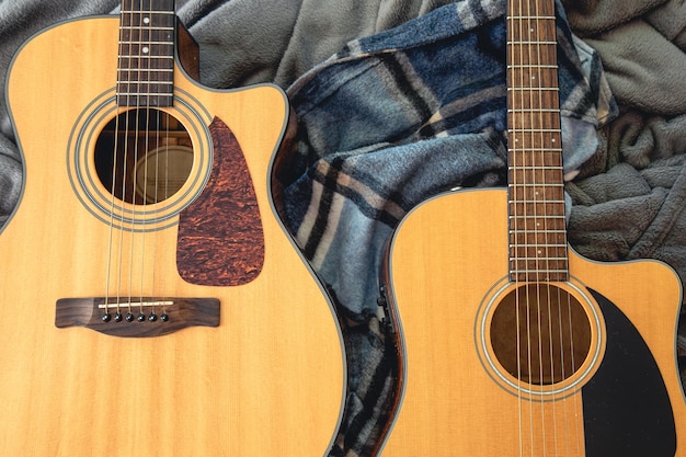 Two acoustic guitars on a cozy plaid top view