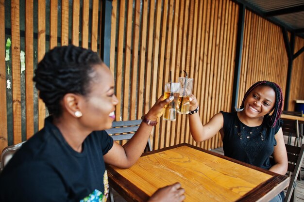 Two african american girls drinking and cheering together