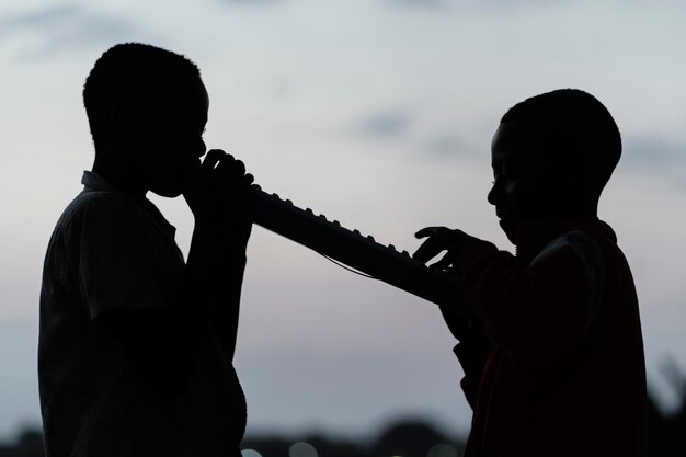 Two african children at sunset playing instrument