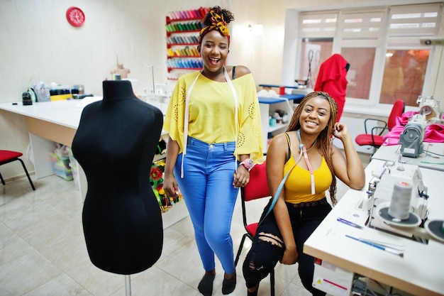 Two african dressmaker woman sews clothes on sewing machine at tailor office Black seamstress girls