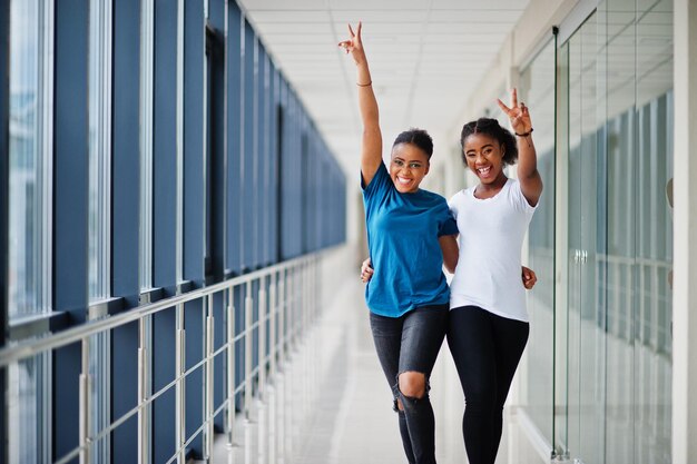 Two african woman friends in tshirts posed indoor together