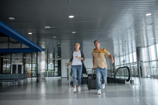 Two airline passengers rushing along the airport terminal