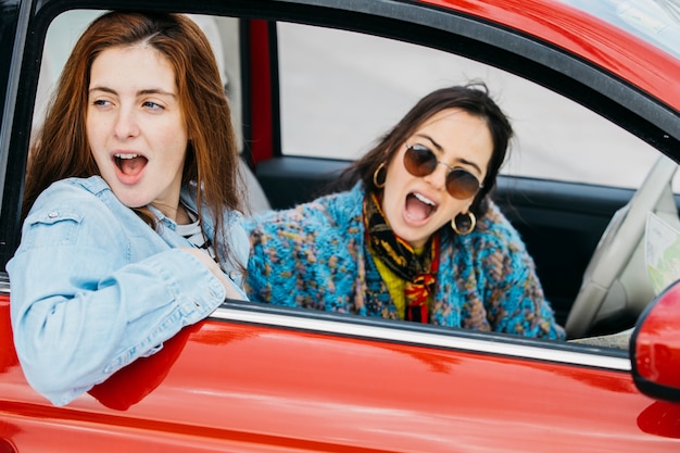 Two amazed women looking out from car window