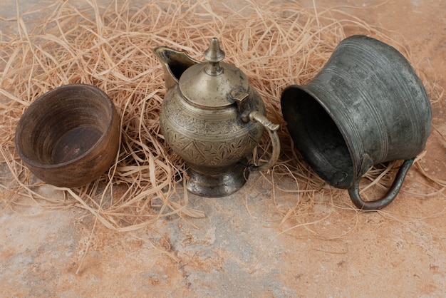 Два древних чайника с пустой деревянной тарелкой на мешковине.