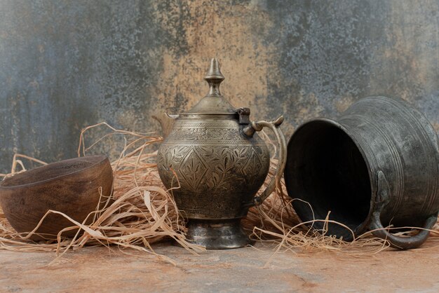 Two ancient kettles with empty wooden plate on burlap.