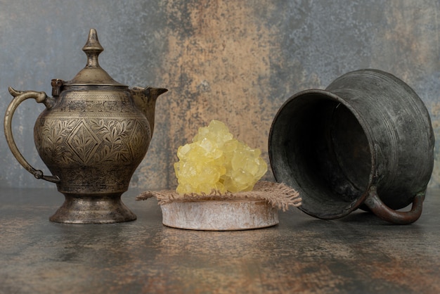 Two ancient kettles with slices of sweet sugar on marble surface. 