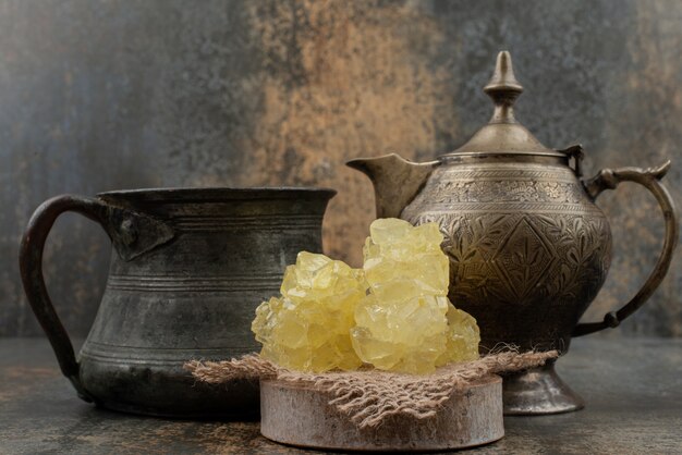 Two ancient kettles with slices of sweet sugar on marble wall.