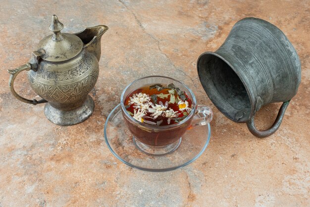 Two ancient teapots with herbal tea on marble background