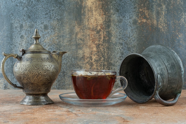 Two ancient teapots with herbal tea on marble background
