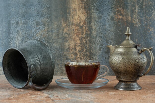 Two ancient teapots with herbal tea on marble background