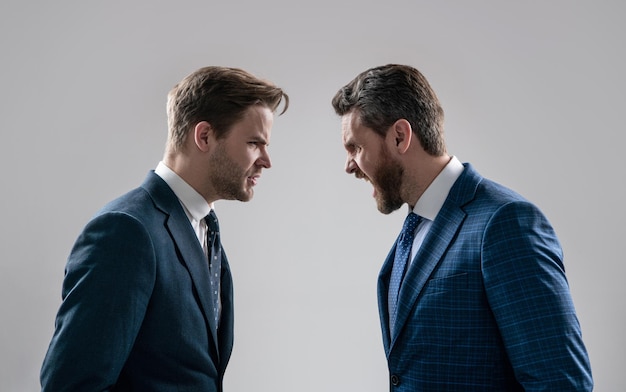 Two angry businessmen shouting face to face arguing having struggle for leadership on businessmeeting have business competition contradiction