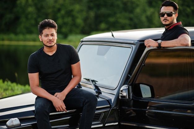 Two asian brothers man wear on all black posed near suv car