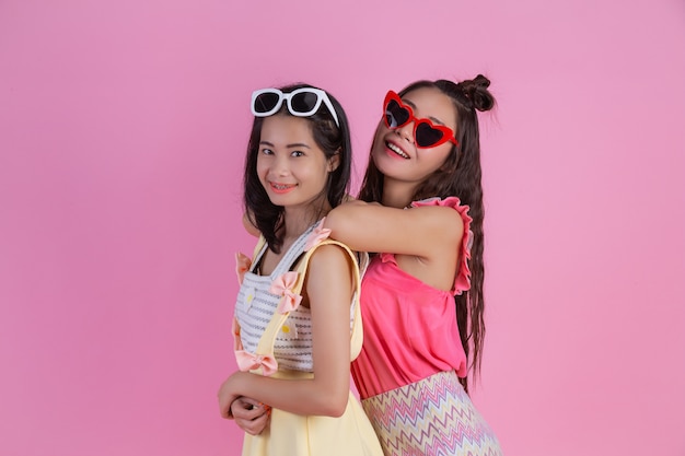 Two Asian girls who are friends are happy and have a pink .