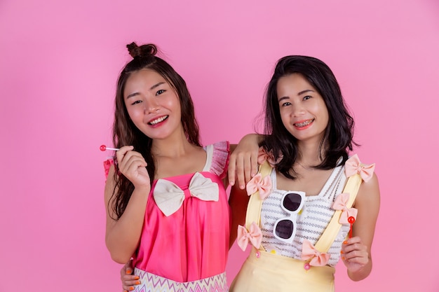 Two Asian girls who are friends are happy and have a pink .