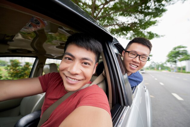 車に乗って道路と外を見て2人のアジア人男性、selfieを取ってドライバー
