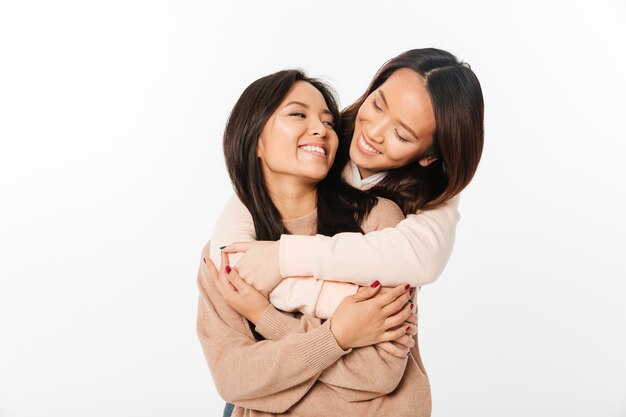 2 азиатских довольно счастливых сестры дам обнимая