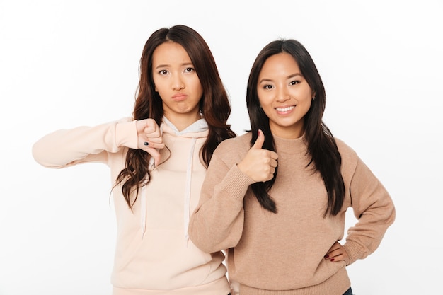 Two asian pretty ladies sisters showing different emotions