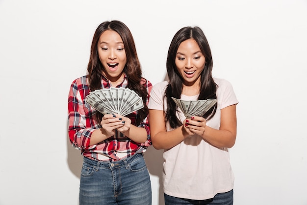 Free photo two asian pretty shocked cute ladies holding money.