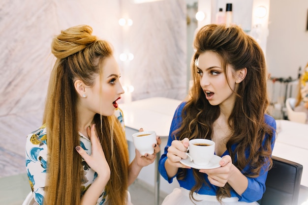 Две удивленные удивленные привлекательные женщины разговаривают в салоне красоты