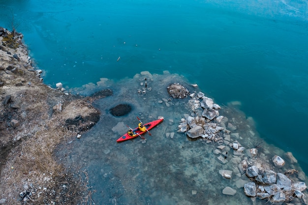 Free photo two athletic man floats on a red boat in river