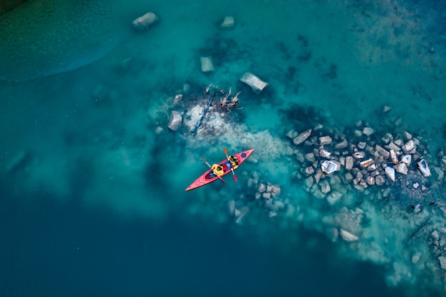 Two athletic man floats on a red boat in river