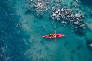 Free photo two athletic man floats on a red boat in river