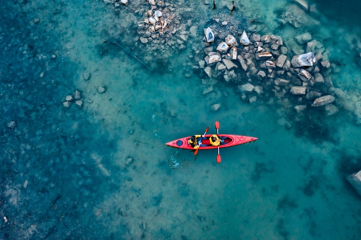 Free Photo two athletic man floats on a red boat in river