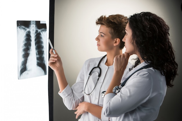 Два привлекательных молодых доктора, смотрящие на результаты рентгена