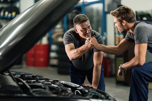 Two auto mechanics giving each other a manly greet in in auto repair shop