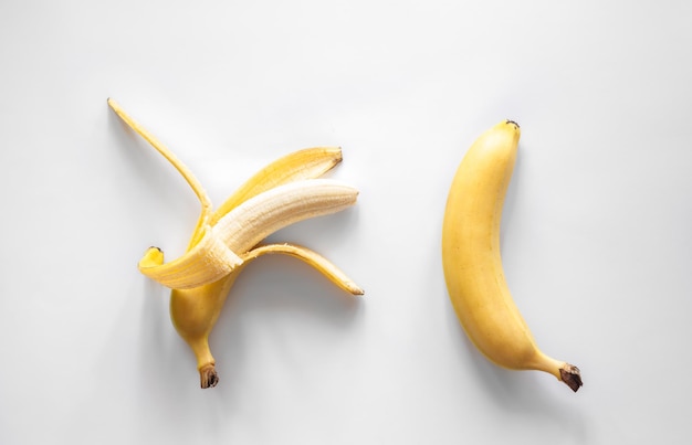 白い背景の上の2つのバナナは概念的なミニマリズムを分離しました